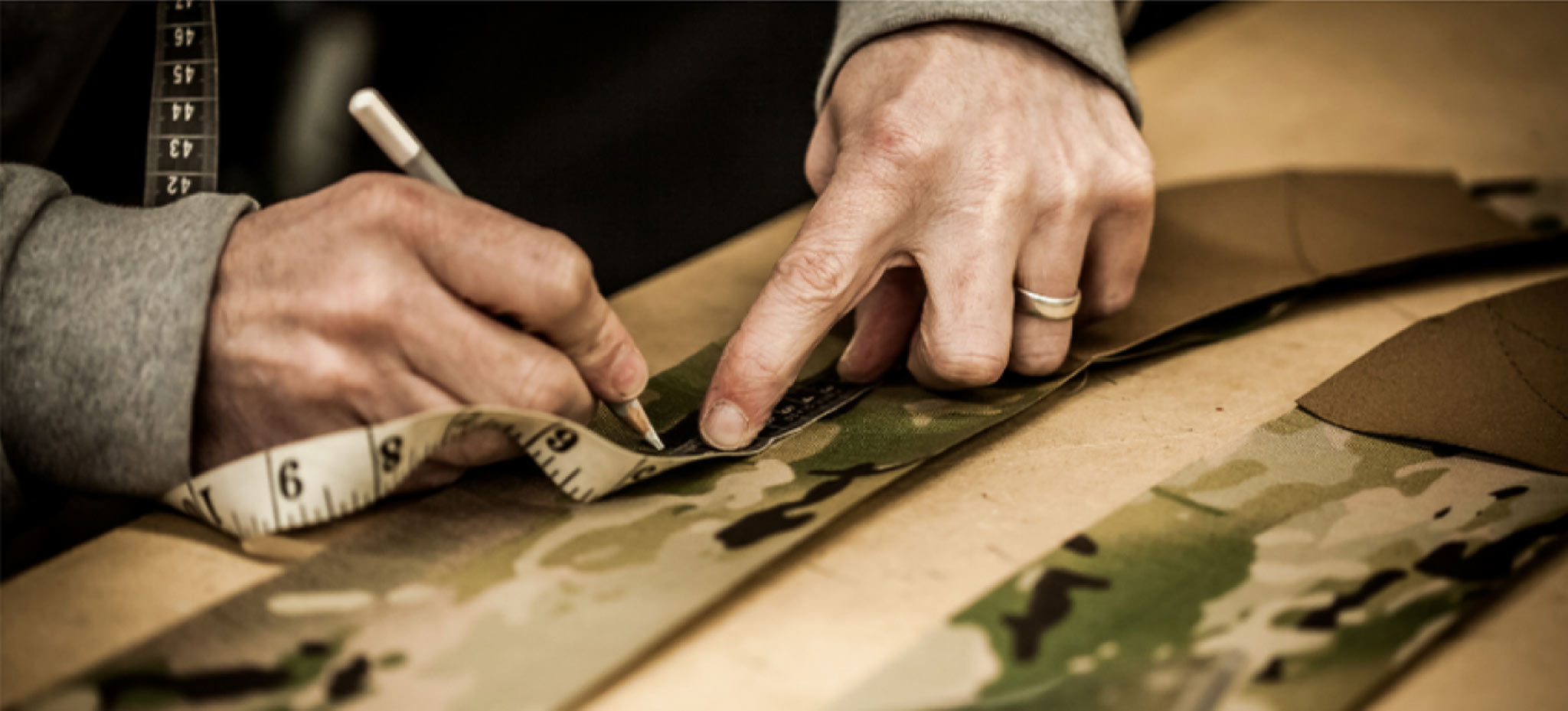 Hands designing Sabre Tactical gear with pencil and tape measure 